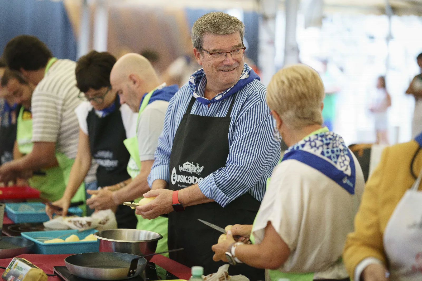 El Alcalde de Bilbao pela una patata, sonriente, en la carpa del certamen gastronómico del Arenal