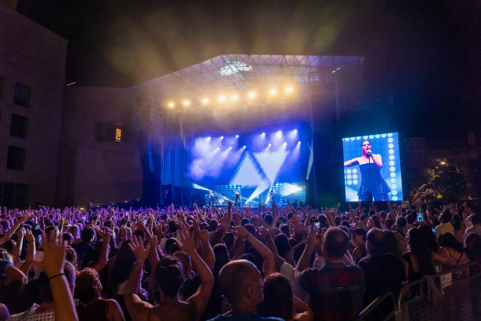 Plano general del escenario de Abandoibarra iluminado, con la explanada llena de público y la pantalla gigante encendida