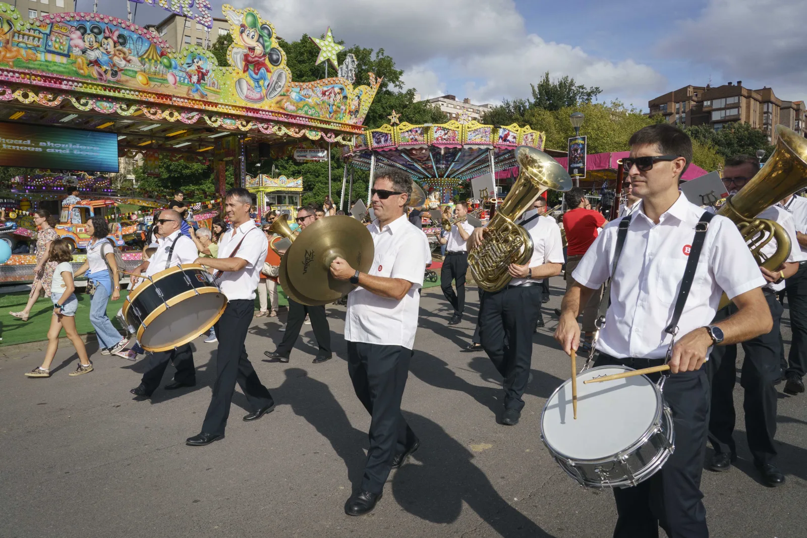 Músicos de una fanfarria tocando entre las atracciones de la feria