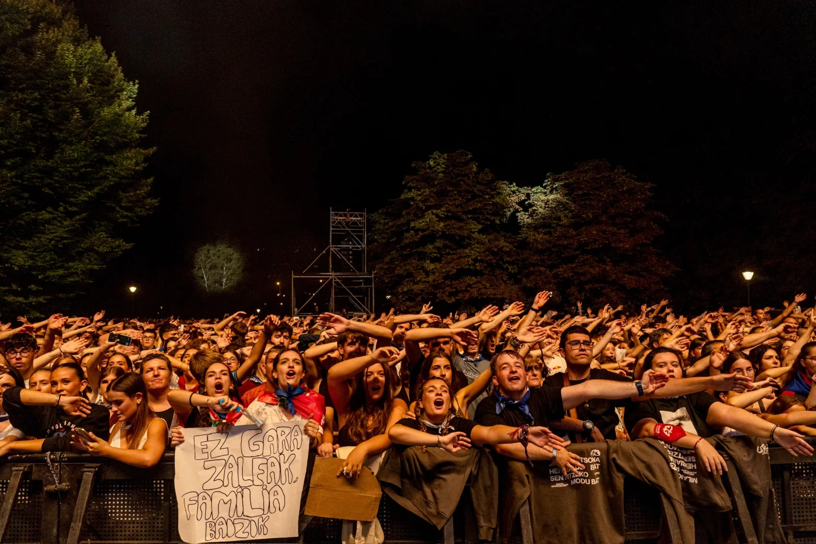Primera fila del concierto contra la valla, con pañuelos rojos y una pancarta hecha a mano que dice «Ez gara zaleak, familia baizik»