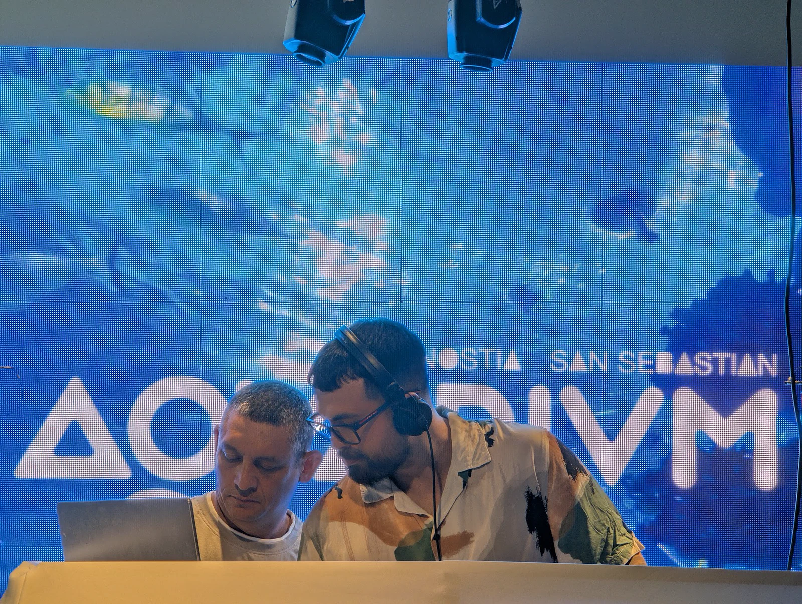 Dos DJ tras la mesa de mezclas durante la cena cóctel, con la pantalla LED del Aquarium iluminada de azul detrás
