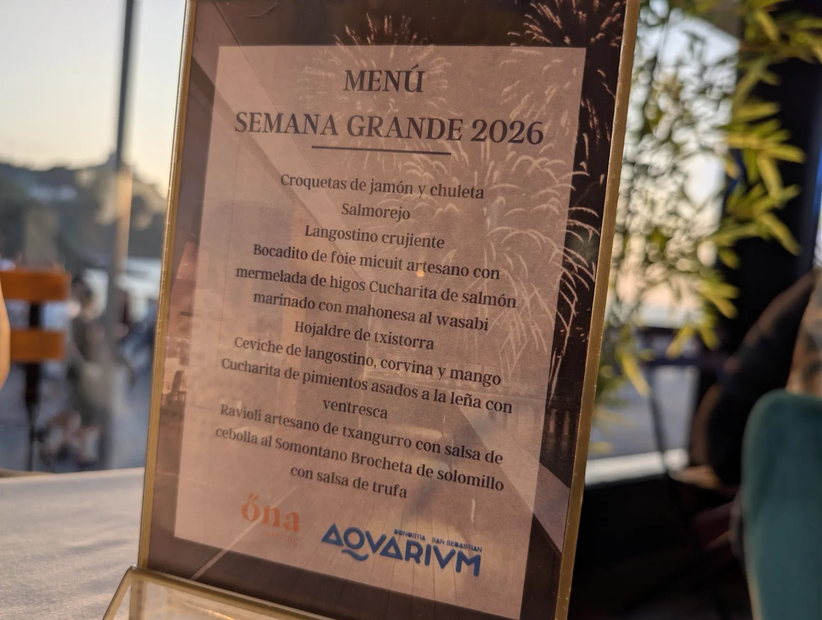 La tarjeta del «Menú Semana Grande 2026» sobre la mesa, con los diez pintxos listados y los logotipos de Ona catering y del Aquarium al pie