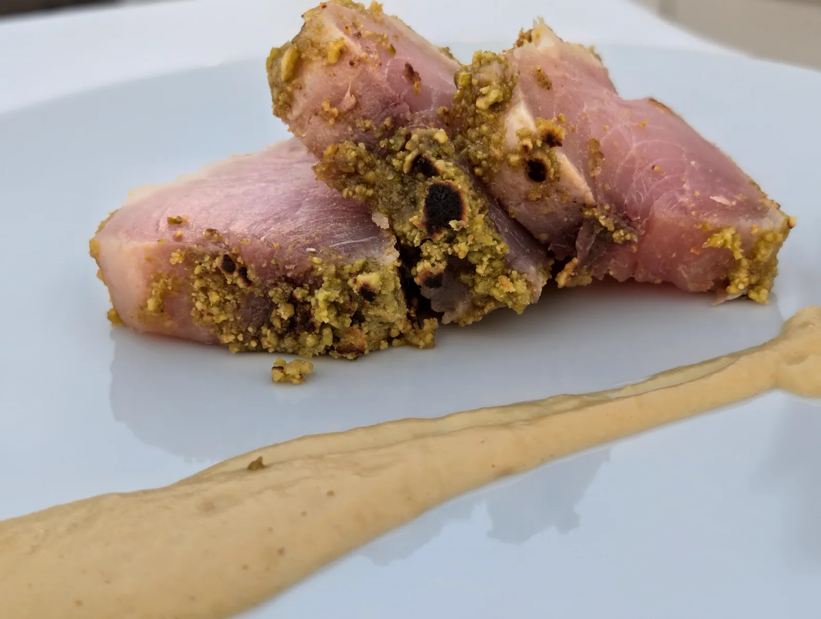 Bonito marinado con costra de pistacho sobre una línea de crema de garbanzos, uno de los dos platos a elegir del menú