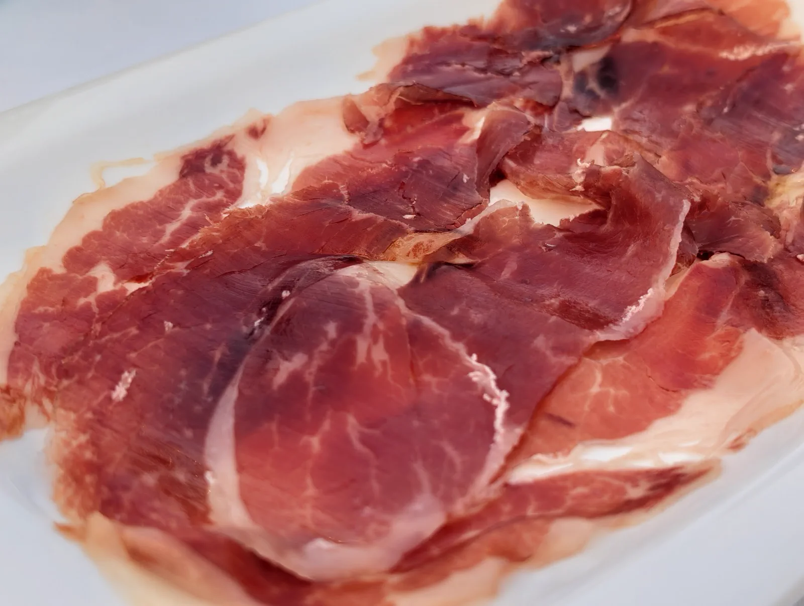 Plato de jamón ibérico Los Pedroches extendido sobre la fuente, segundo pase del menú de Semana Grande de La Perla