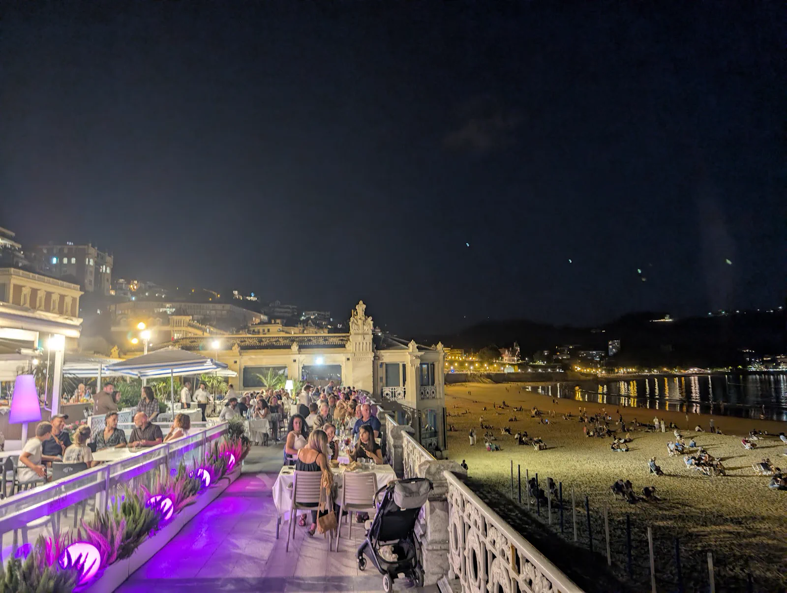 El paseo y la arena de la Concha llenándose de gente que coge sitio para ver los fuegos artificiales
