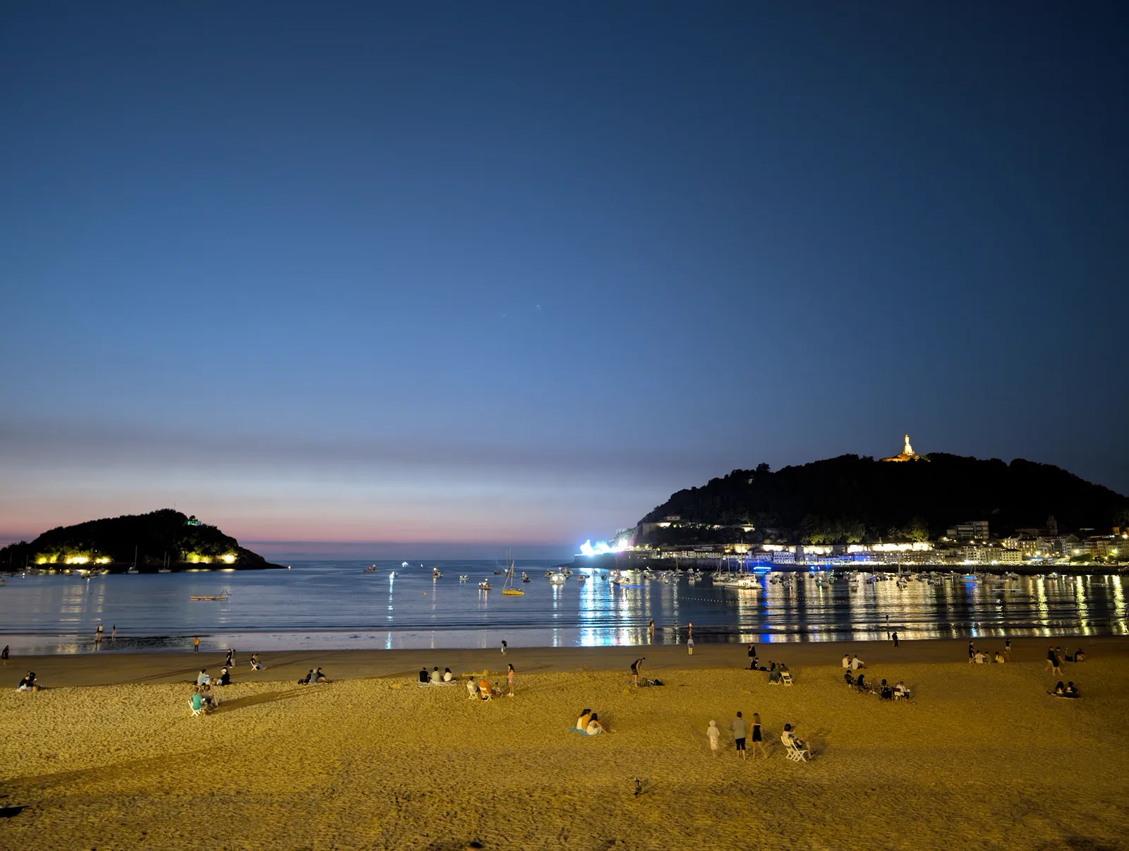 La playa de la Concha en la hora azul, con la isla de Santa Clara iluminada y las luces del paseo reflejadas en el agua