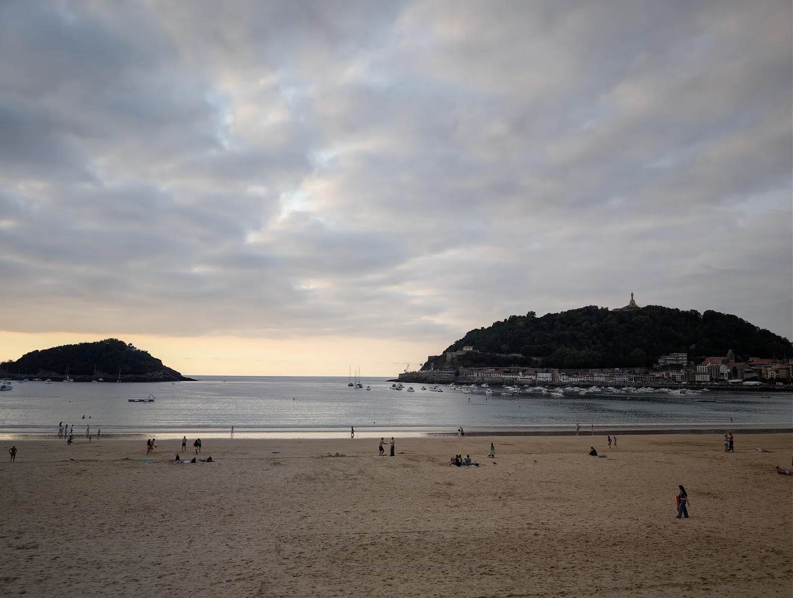 La bahía de la Concha vista desde la terraza de La Perla antes de cenar, con el cielo cubierto, la playa a media tarde y el monte Urgull al fondo