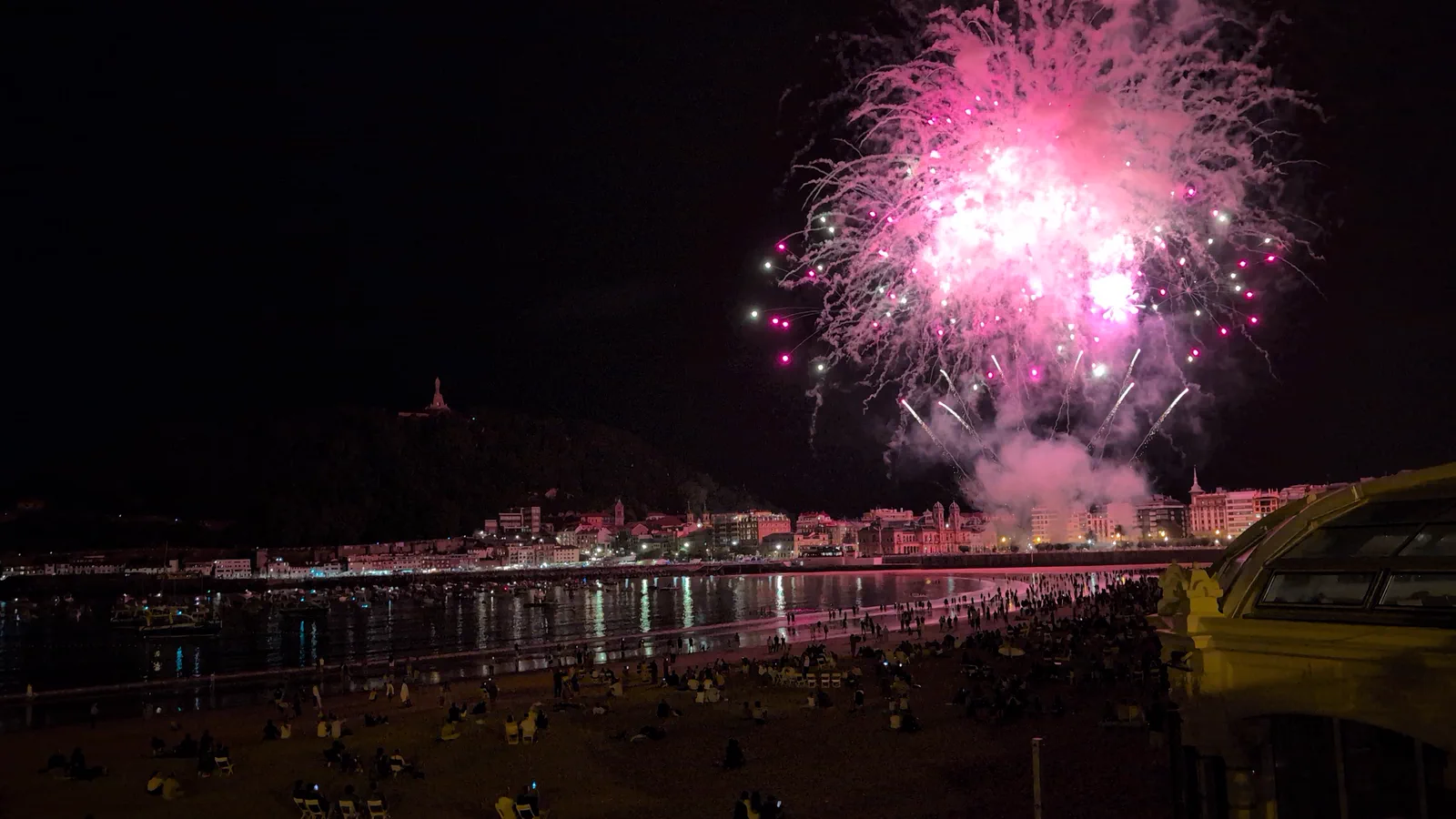 Fuegos artificiales rosas sobre la bahía de la Concha con el reflejo cayendo entero sobre el agua