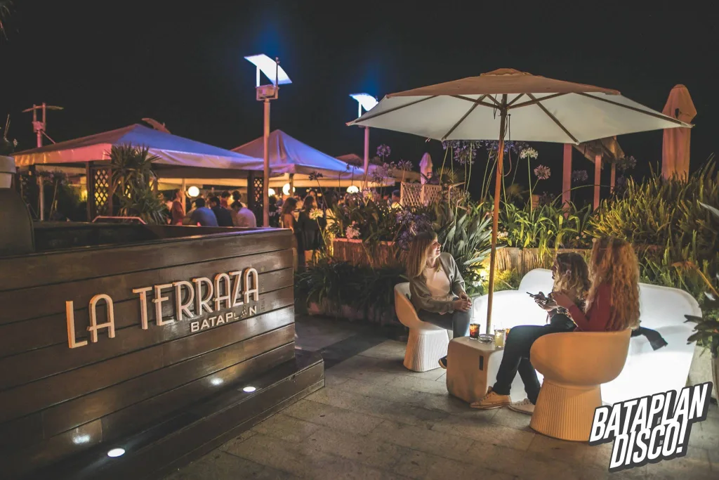 La terraza del Bataplán de noche, con sofás blancos y sombrillas junto al rótulo «La Terraza Bataplán»