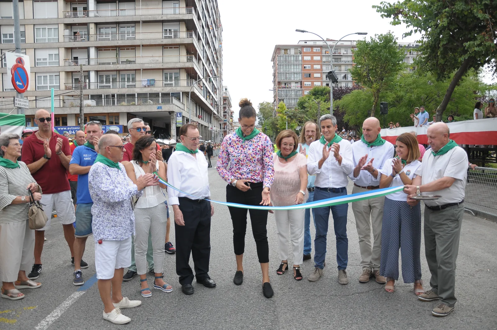 Corte de la cinta verde, blanca y azul que abre el circuito del desfile, rodeado de autoridades y vecinos con pañuelo verde